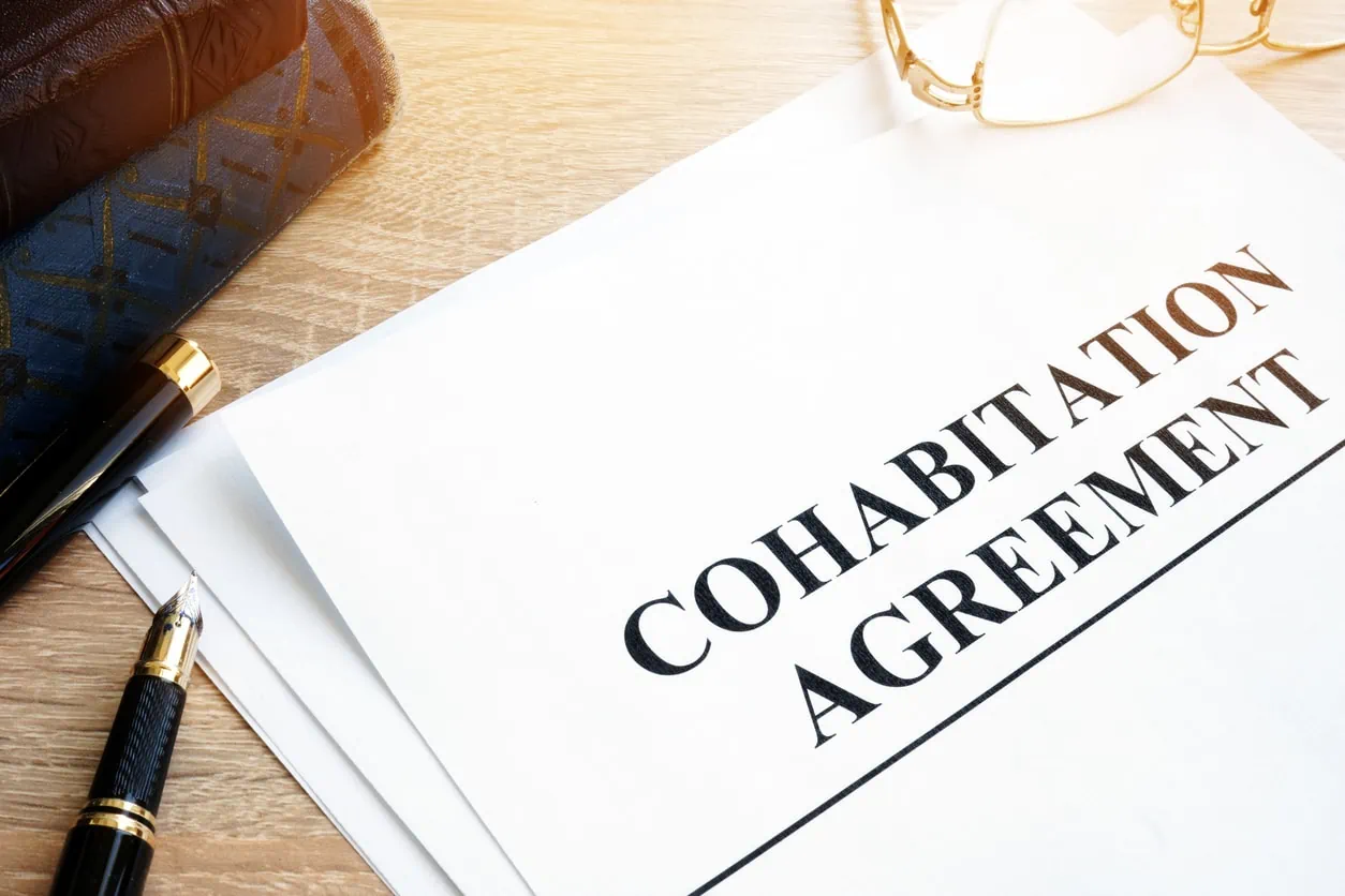 A document that reads "Cohabitation Agreement." A pen and a pair of eyeglasses lie next to the document.
